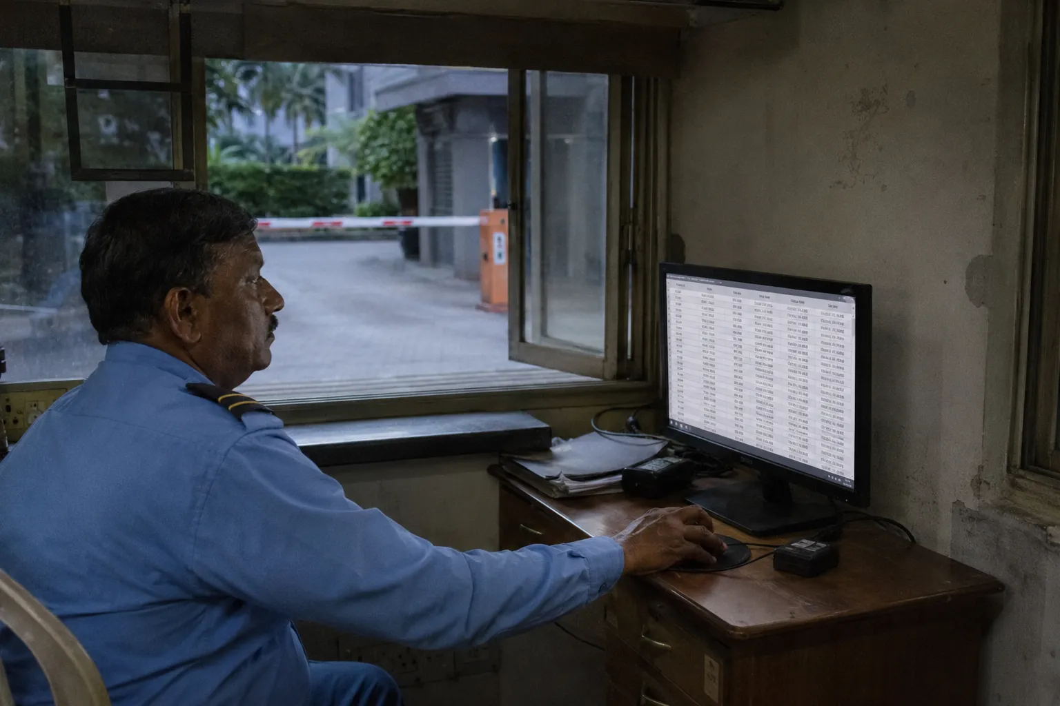 Security guard at a gatehouse monitor reviewing the vehicle entry log