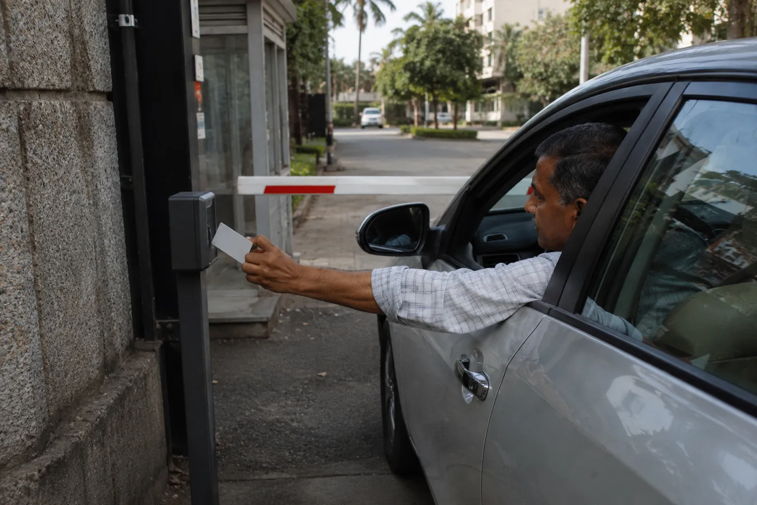 Driver holding an RFID card up to a reader at the exit gate