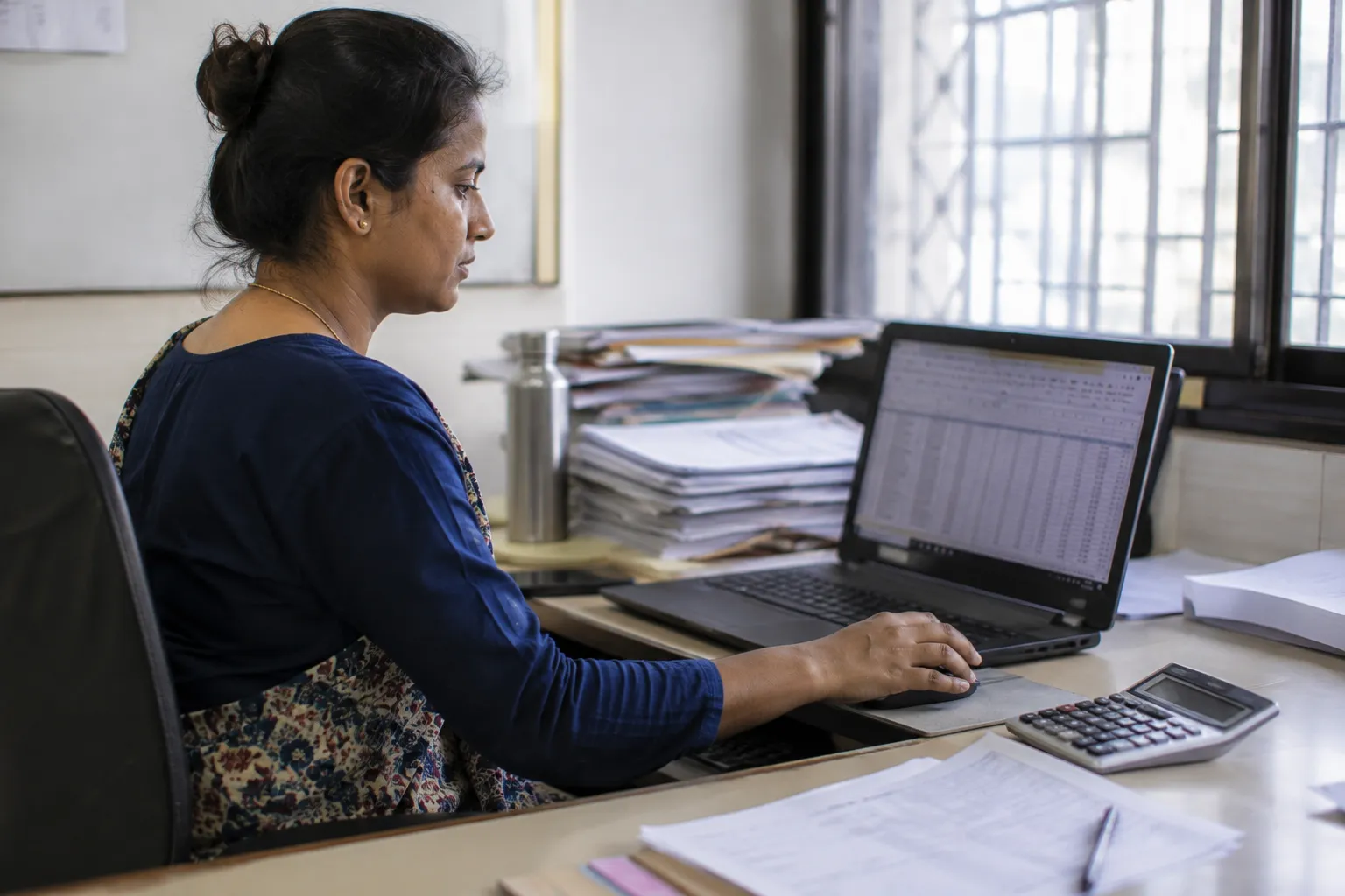 Accounts clerk processing a one-click bank salary transfer at a desk