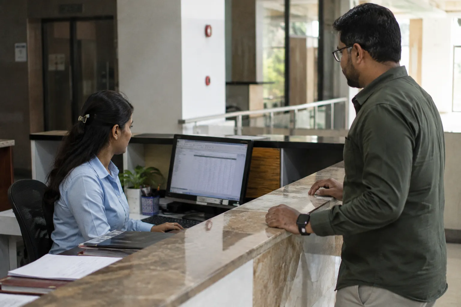 Receptionist checking a visitor's name against a pre-approved appointment list
